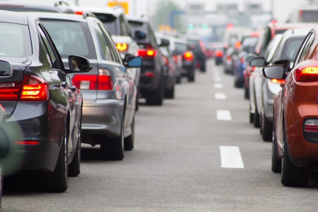 Cars lined up in traffic on a road.