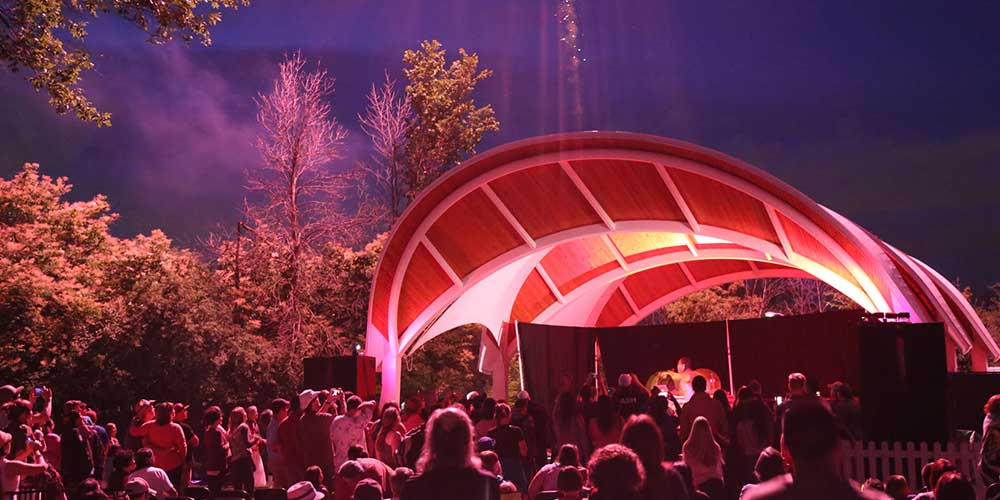 An outdoor stage with lots of people in the audience at night