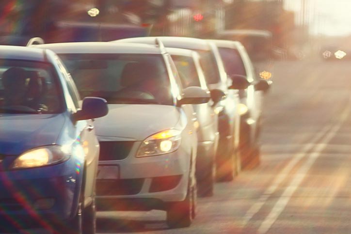 Cars lined up on road with sunset in background