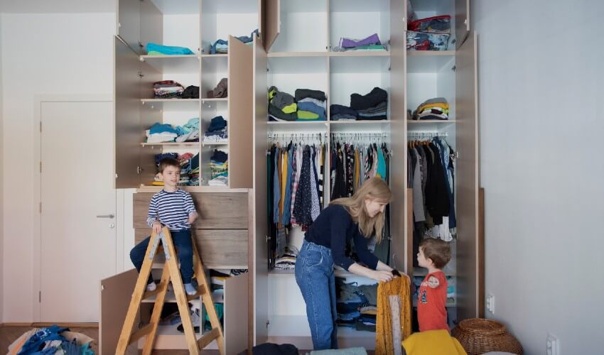 Mom organizing closet with two sons.