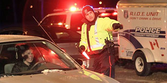 A police officer pointing a driver to a R.I.D.E check