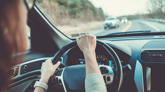 A woman's hand on a steering wheel.