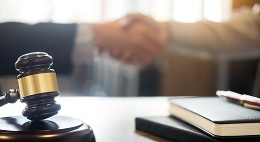 Gavel with two people shaking hands in the background