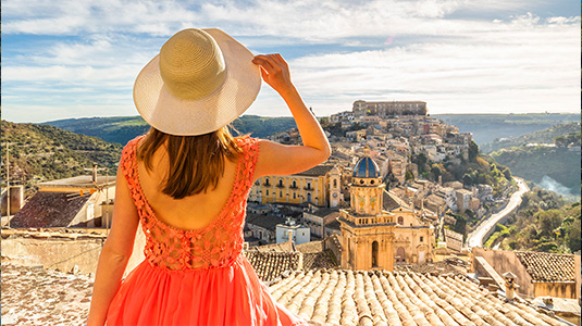 Woman with hat looking at Sicilian architecture